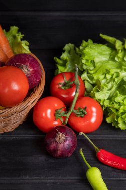 Taze olgun sebzelerle dolu bir hasır sepet. Koyu ahşap bir masanın üzerine yerleştirilmiş. Yüksek kalite fotoğraf