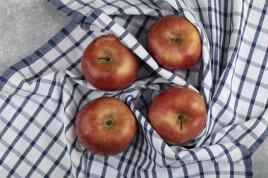 Mermer zemin üzerinde çizgili masa örtüsü olan lezzetli kırmızı elmalar. Yüksek kalite fotoğraf