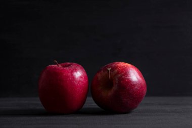 Su damlalarındaki kırmızı elmalar koyu ahşap bir masaya konur. Yüksek kalite fotoğraf