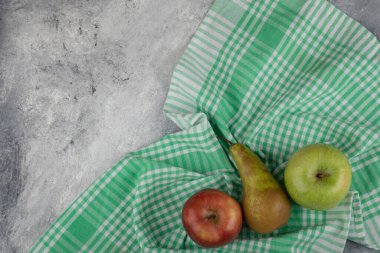 Yeşil ve kırmızı elmalar, mermer zemin üzerinde çizgili masa örtüsü olan armut. Yüksek kalite fotoğraf