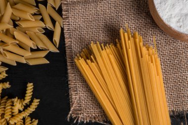 İple bağlanmış pişmemiş spagetti ve ahşap bir masaya yerleştirilmiş çiğ makarna. Yüksek kalite fotoğraf