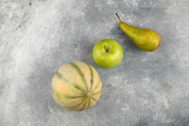 Yeşil elma, armut ve mermer zemin üzerinde küçük kavun. Yüksek kalite fotoğraf