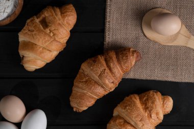 Sade kruvasanlar, bir kase un ve tahta yüzeyde çiğ yumurta. Yüksek kalite fotoğraf