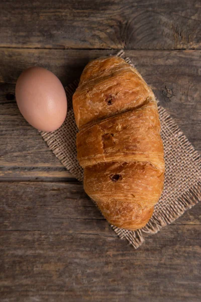 新鲜烘焙的牛角面包 用褐色鸡蛋放在木制桌子上 高质量的照片 — 图库照片
