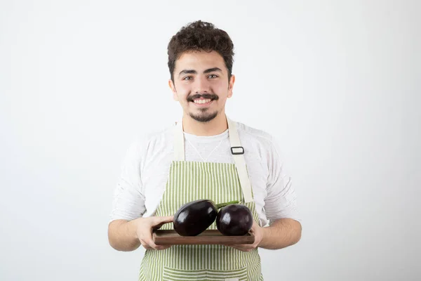 Joven Cocinero Macho Delantal Sosteniendo Plato Berenjenas Grandes Sobre Fondo —  Fotos de Stock