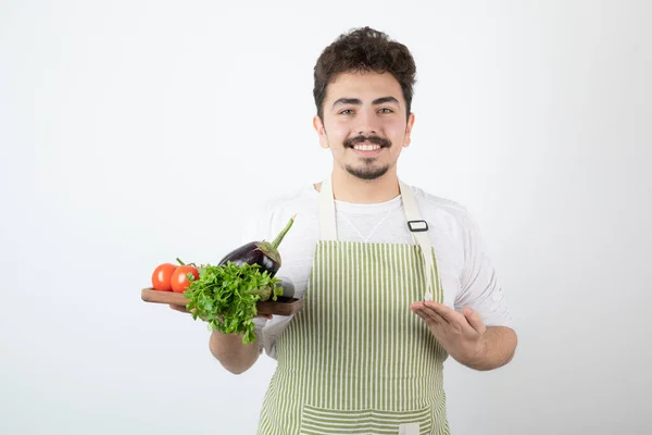 Imagen Hombre Sonriente Delantal Sosteniendo Una Tabla Madera Con Verduras —  Fotos de Stock