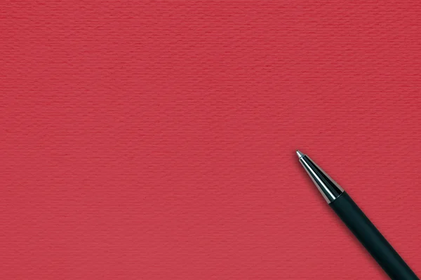 Black ball pen on the red paper background — Stock Photo, Image