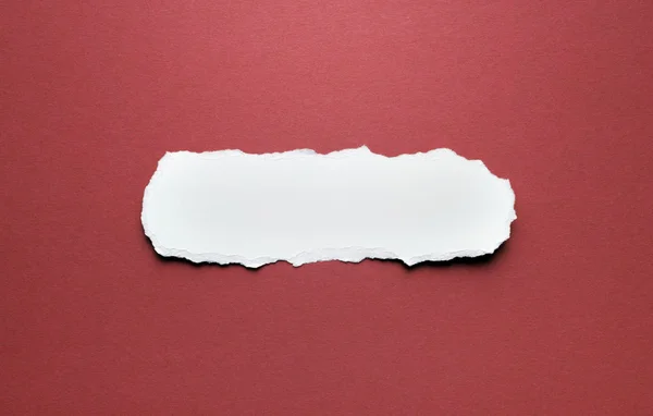 Un trozo de papel roto sobre un fondo rojo — Foto de Stock