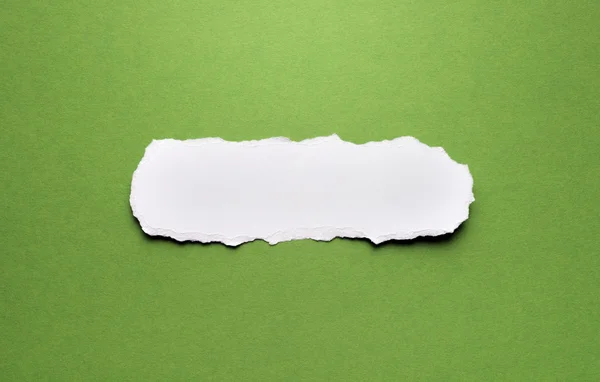 Кусок рваной бумаги на зеленом фоне — стоковое фото