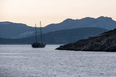 Gizemli yelkenli. Yalnız bir yelkenli gemi akşam yola çıkar. Karanlık deniz, dağların arka planında..