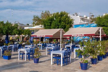 BODRUM, TURKEY - 19 Ekim 2020: Bodrum 'un deniz cephesinde ekose masa örtüleri ve mavi sandalyeli rahat Türk tarzı kafe.