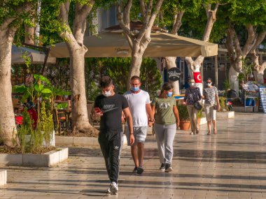 BODRUM, TURKEY - 19 Ekim 2020: Koronavirüs salgını sırasında maskeli insanlar Bodrum 'un gezinti alanı boyunca yürür.