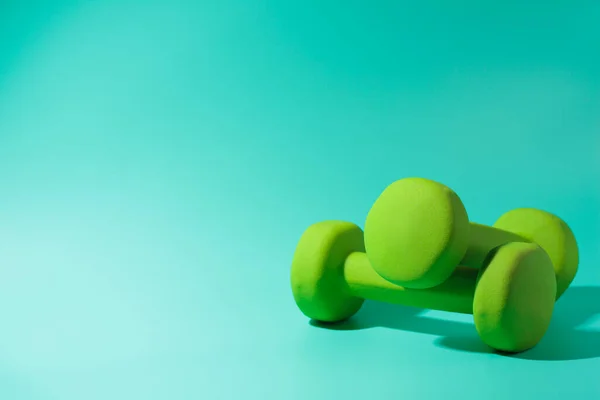 fitness dumbbells on turquoise background with a hard shadow. Stock photography