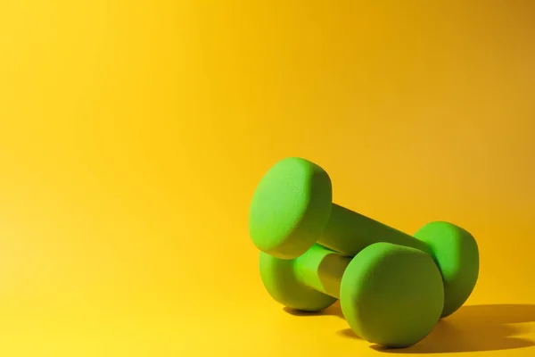 fitness dumbbells on a yellow background with a hard shadow. Stock photography