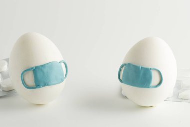 Beyaz arka planda koruyucu ilaç maskesiyle paskalya yumurtaları. Paskalya karantinası. COVID-19 'u durdurun..