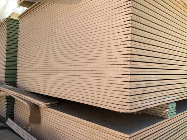 Piled sheets of drywall at the construction site. Stacked plasterboard sheets. Gypsum cardboard