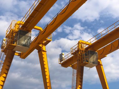 Gantry vinçleri bulutlu gökyüzünün karşısında. Endüstriyel kaldırma makineleri. Çekin, vinç.