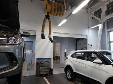 Asansörde açık motor kaputu ve araba servisinde beyaz SUV olan bir araba. Podolsk, Moskova bölgesi - Nisan 2019