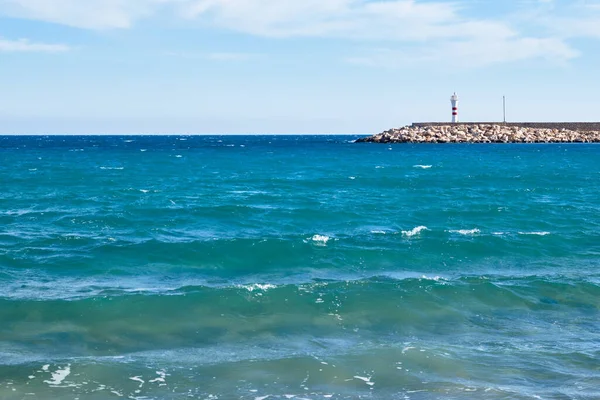 Paisaje con mar ondulado y faro en muelle de piedra — Foto de Stock