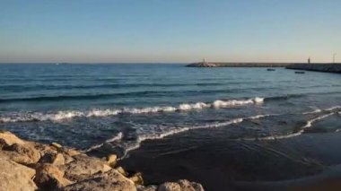 Akşam sörfünün zamanı. Limandaki taş iskelelerdeki deniz fenerleri.