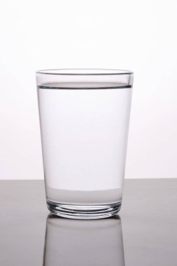 Boş bir bardak su, arka planda ışık yansıması ile yakalanır.
