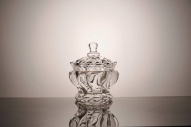 Kapağı ve gri arka planda yansıması olan boş cam kase.