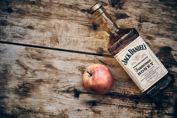杰克 · 丹尼尔斯蜂蜜甜酒和苹果果在风吹日晒的木制背景下 — 图库照片