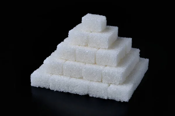 Pila di cubetti di zucchero bianco su sfondo nero — Foto Stock