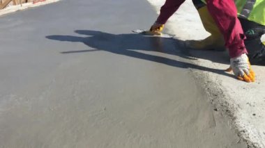 İnşaat işçisi yeni dökülmüş betonu malayla cilalıyor