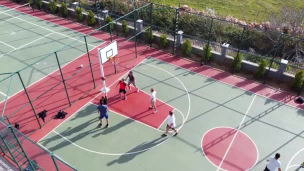 Homens jogam streetball na vista aérea quadra ao ar livre — Vídeo de Stock