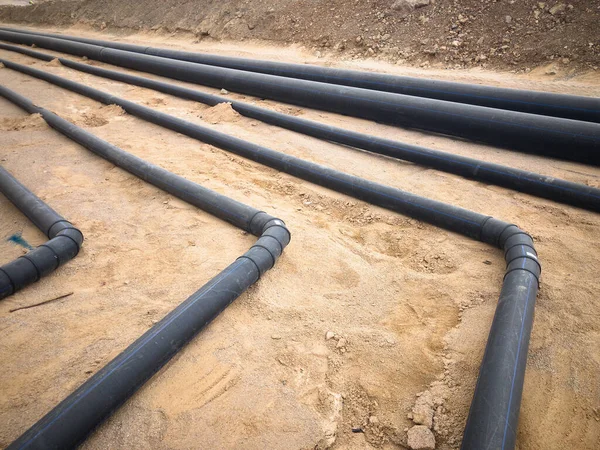 Black plastic water pipes laid on sand foundation — Stock Photo, Image