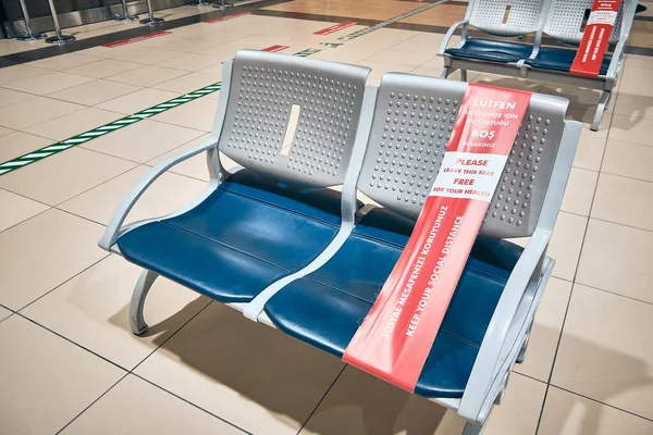 Asientos en el salón del aeropuerto atados con cinta adhesiva para proporcionar distanciamiento social — Foto de Stock