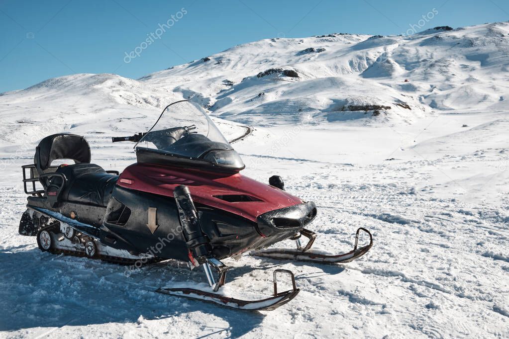 Snowmobile against snow covered slope at background