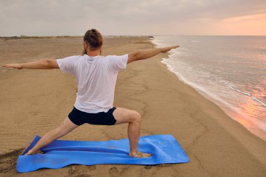 İnsan, deniz kıyısında ikinci derece savaşçı pozu verir.