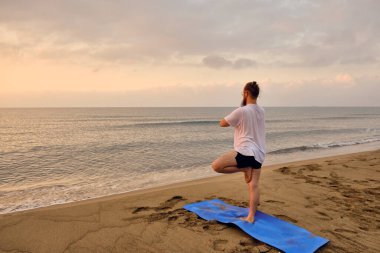 Adam ağaçta duruyor Sahilde asana pozu veriyor