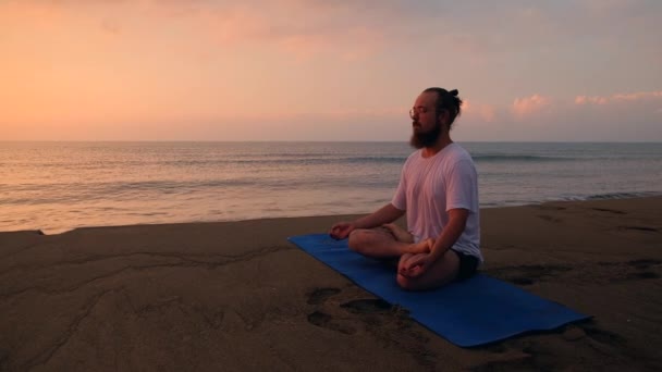 L'homme est assis en position lotus à la plage — Video