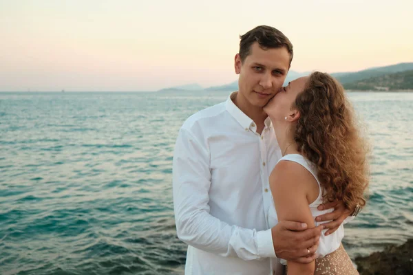 Pareja en una fecha contra la puesta de sol junto al mar — Foto de Stock