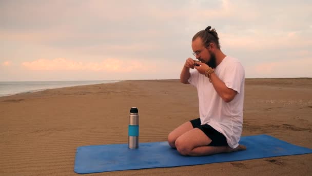 Человек пьет чай на пляже — стоковое видео