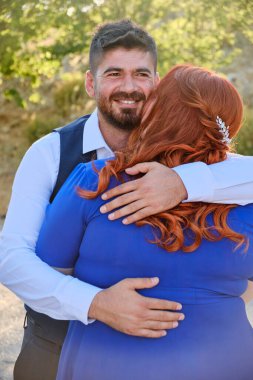 Adam gülümseyerek sevgilisine sarılır.