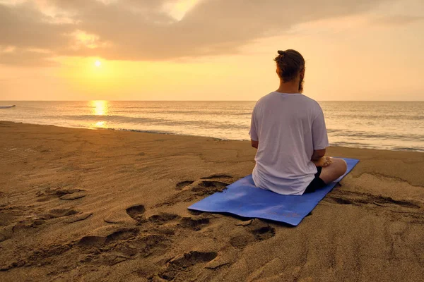 Man sits in lotus position at beach — Stock Photo, Image