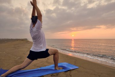 İnsan, deniz sahilinde bir pozla savaşçı olmayı öğrenir.
