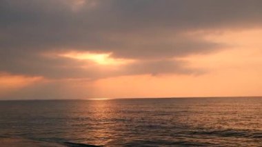 Issız kumsalda bulutlu gün doğumu