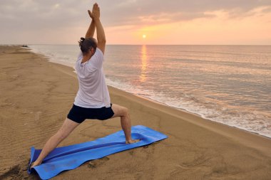 İnsan, deniz sahilinde bir pozla savaşçı olmayı öğrenir.