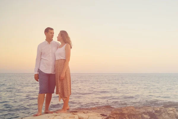 Couple de jeunes adultes contre la mer dans les rayons du soleil couchant — Photo