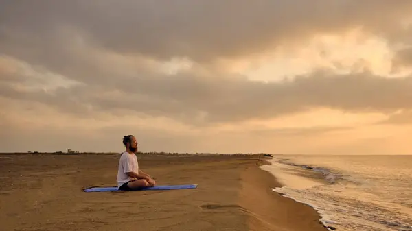 Портрет человека, медитирующего на пляже — стоковое фото