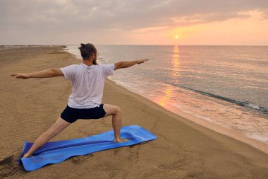 İnsan, deniz kıyısında ikinci derece savaşçı pozu verir.