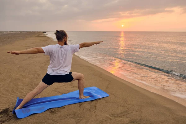 İnsan, deniz kıyısında ikinci derece savaşçı pozu verir.