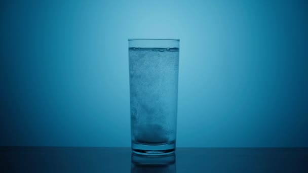 Effervescent tablet dissolves in a glass of water — Stock Video