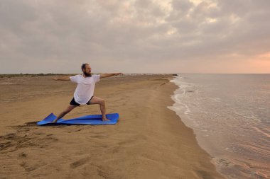 İnsan, deniz kıyısında ikinci derece savaşçı pozu verir.