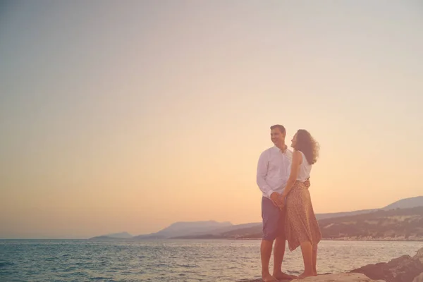 Jong volwassen paar tegen zee in de stralen van de ondergaande zon — Stockfoto